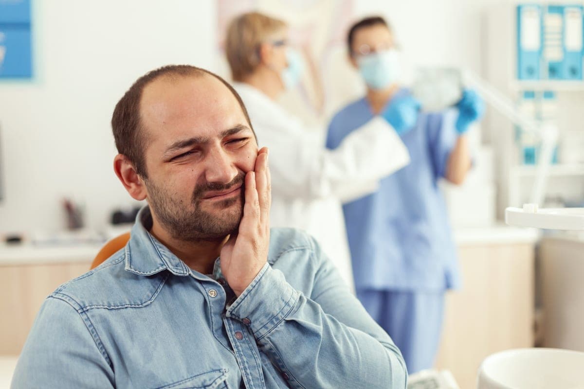 Patient holding her jaw in pain before seeing an emergency dentist in Clearwater
