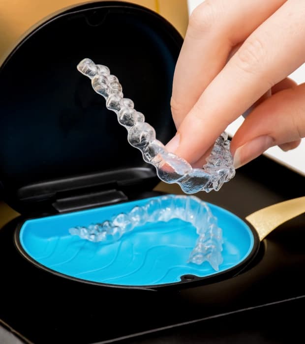 Patient holding a clear aligner during Invisalign treatment in Clearwater, FL